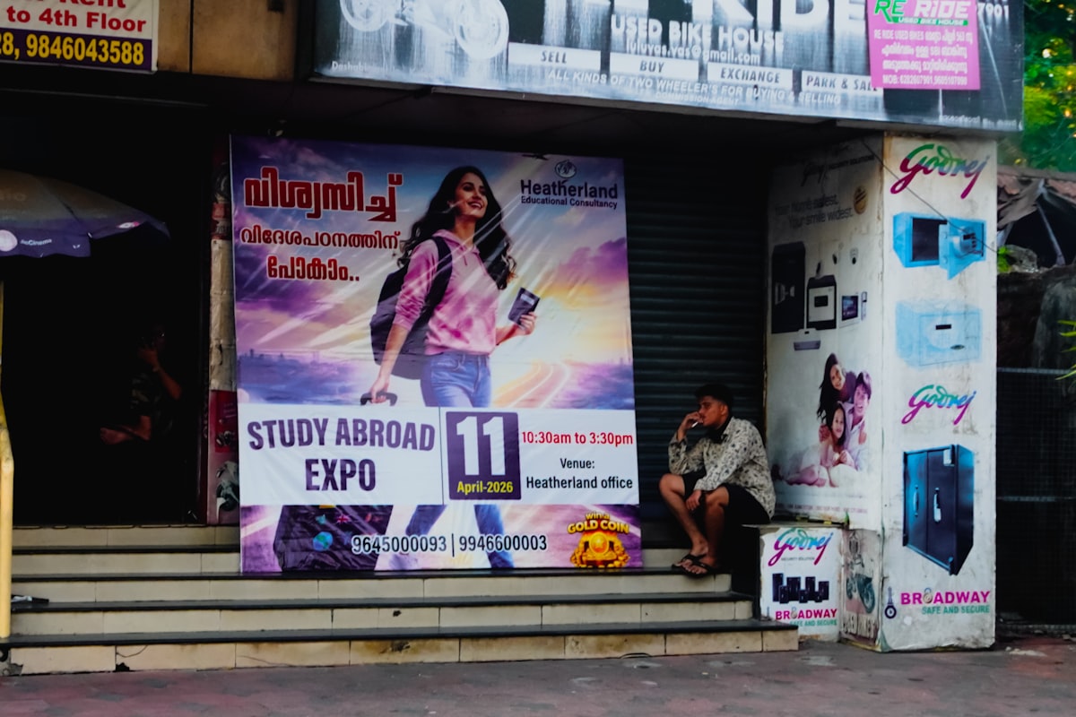 Man sitting near a large "study abroad expo" advertisement.